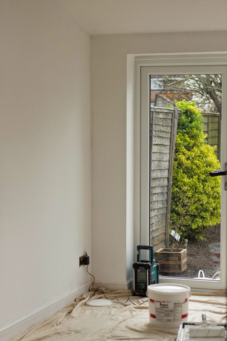 a room that has been painted white and is being worked on by someone with a paint roller