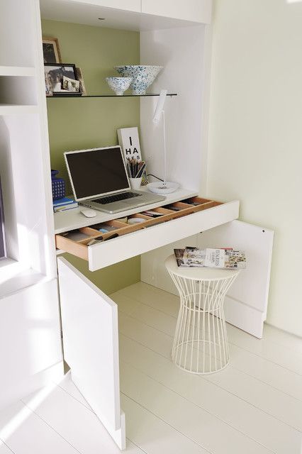 a laptop computer sitting on top of a wooden desk next to a white shelf filled with books