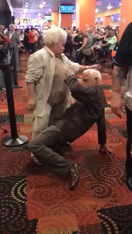 an older man is dancing with another old man in the middle of a room full of people