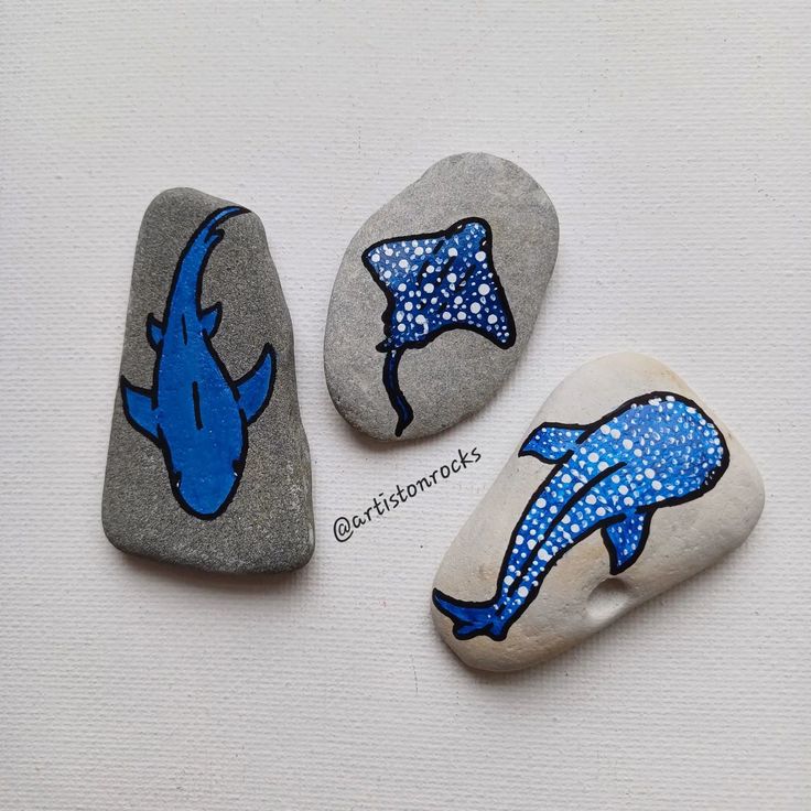 three painted rocks sitting on top of a white surface