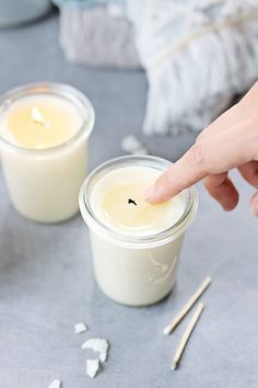 a person is pointing at two small jars with food in them on a gray surface