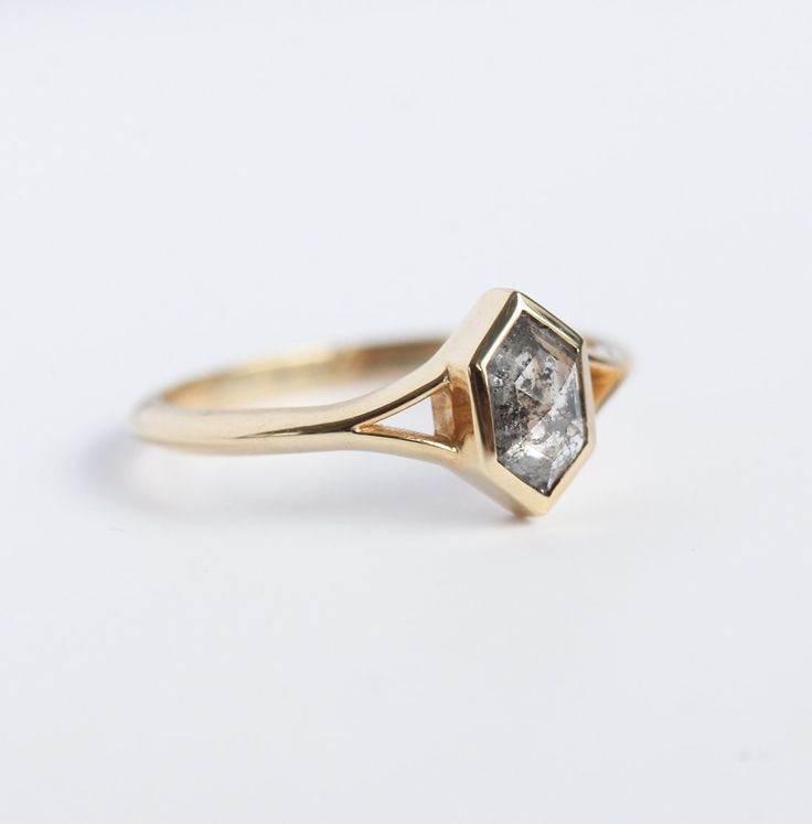 a yellow gold ring with a white diamond in the center on a white background,