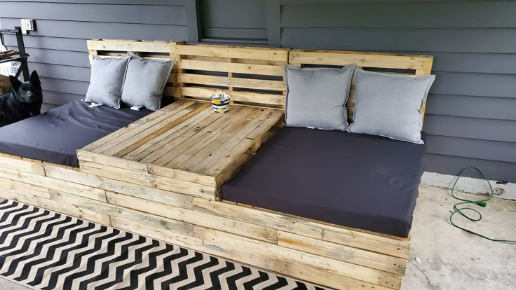 a bed made out of wooden pallets with pillows on the top and bottom side