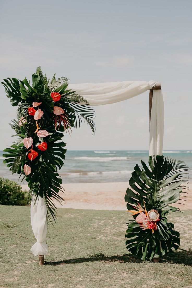 an outdoor wedding ceremony setup with flowers and greenery on the grass by the beach