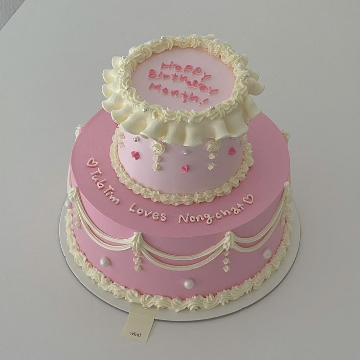 a three tiered cake with pink frosting and white icing on the top