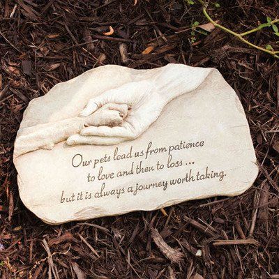 a memorial stone laying on the ground with flowers around it