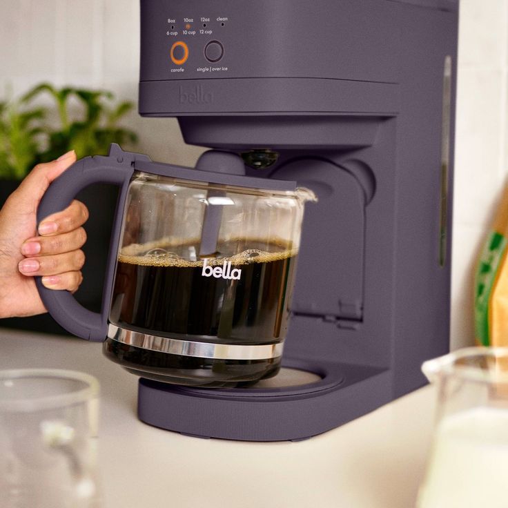 a person is holding up a coffee maker