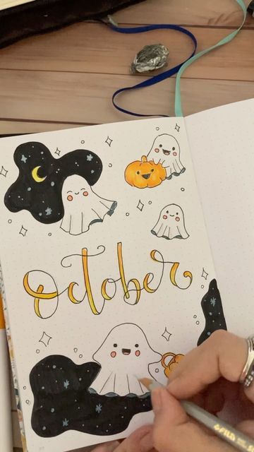 someone is writing in a notebook with halloween decorations on the pages and ghostes around them