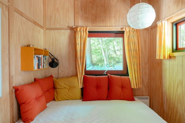 a bed in a room with wood paneling and orange pillows on top of it