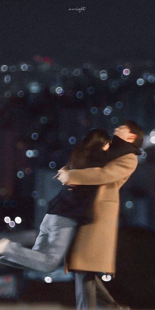 a man and woman are hugging in front of the city lights