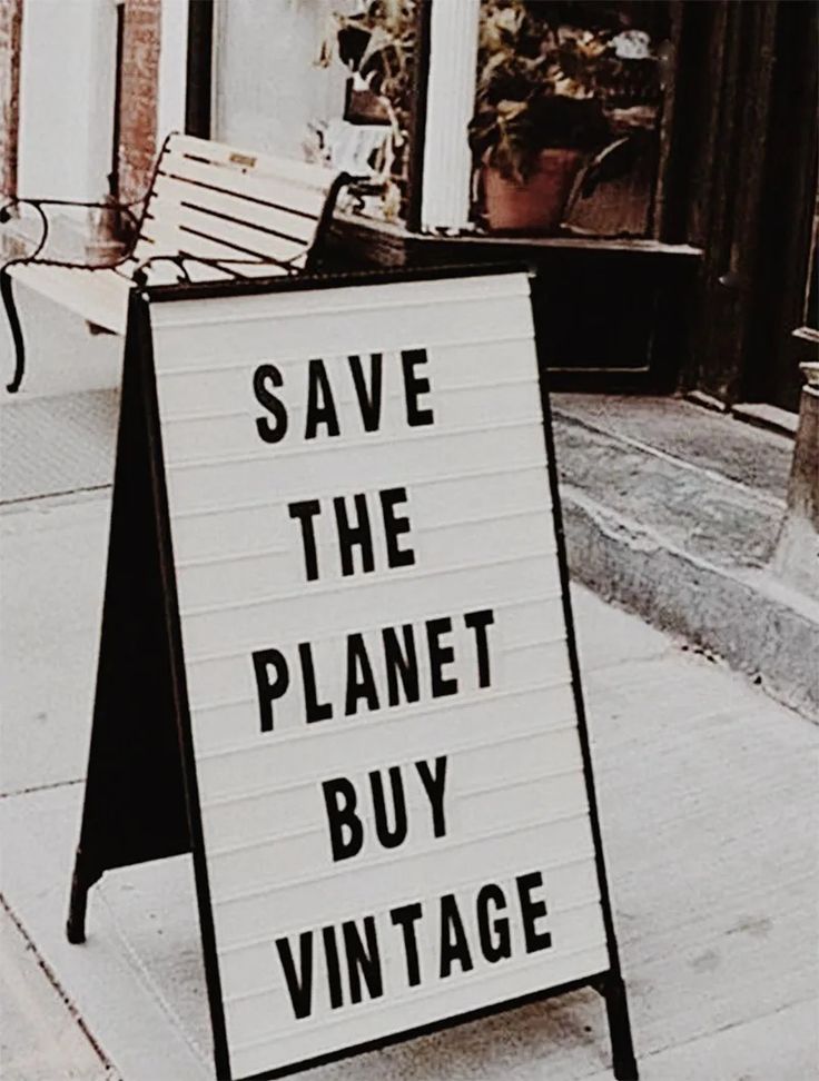 a black and white sign that says save the planet buy vintage next to a bench