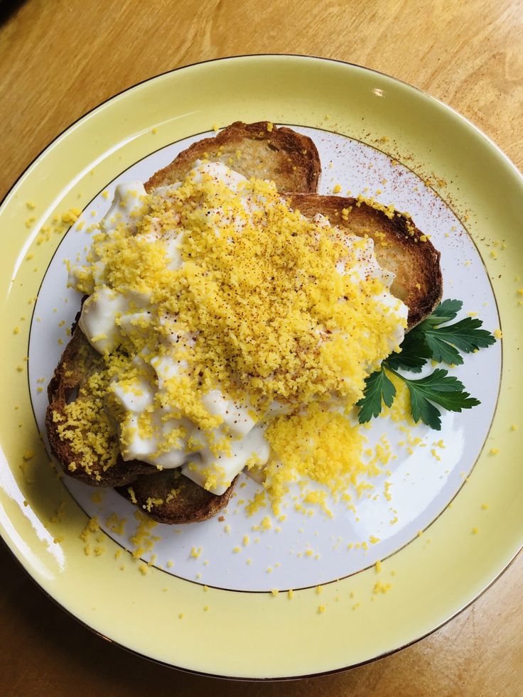 a yellow plate topped with two pieces of toast covered in cheese and parmesan