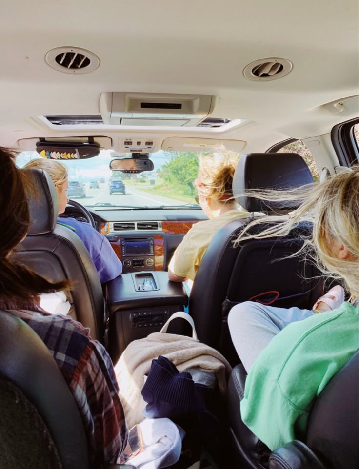 three people sitting in the back seat of a car