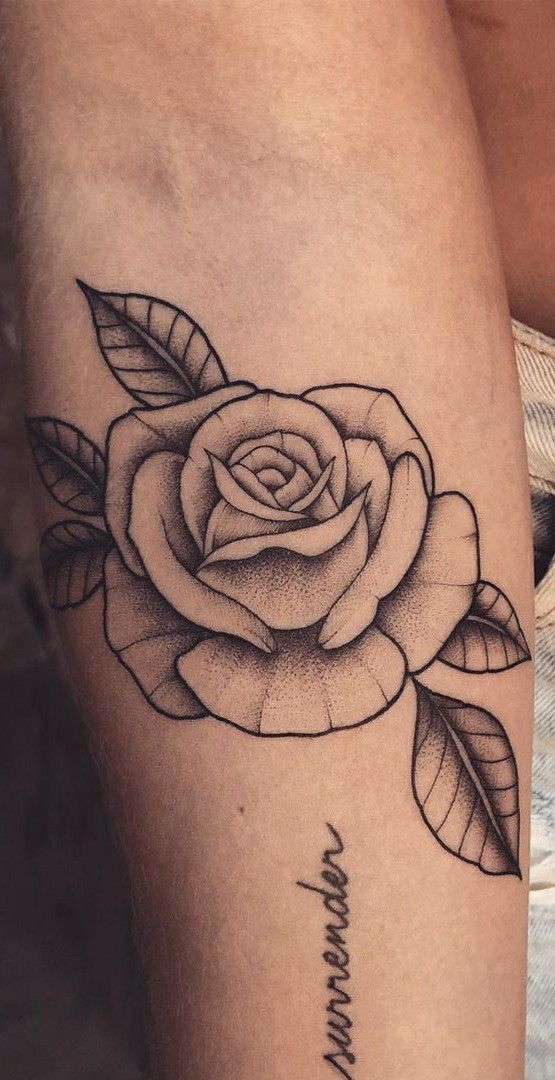 a black and white rose tattoo on the leg, with words written in cursive writing