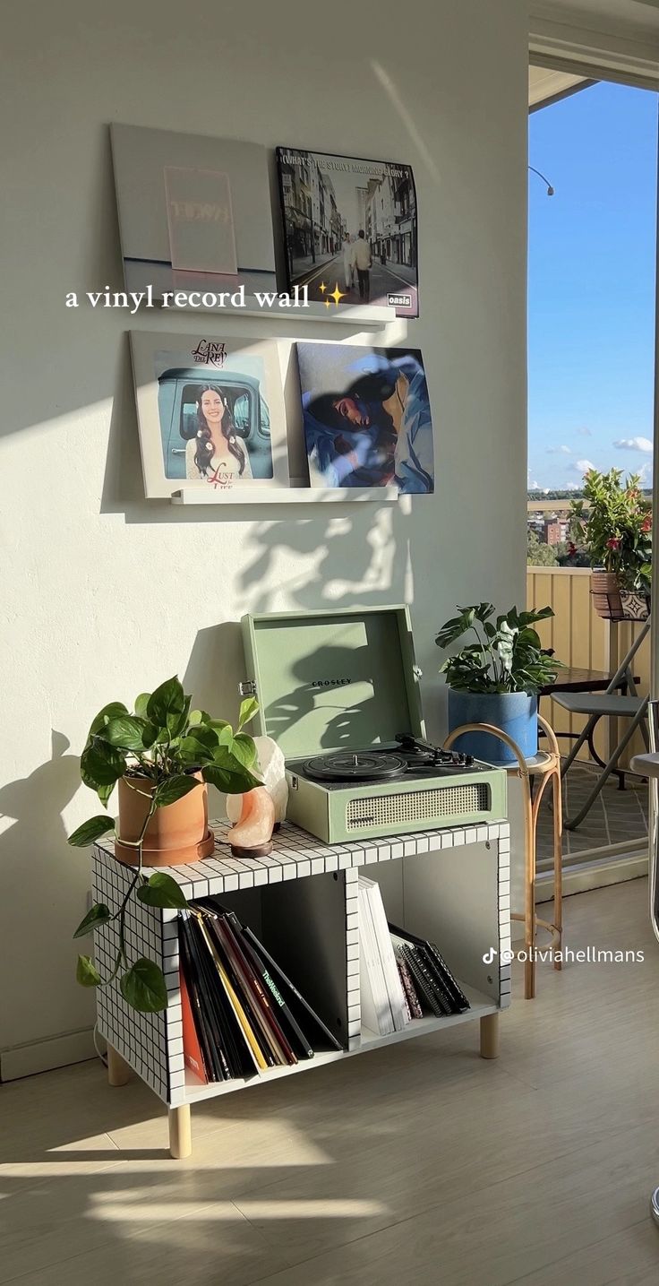 an open record player sitting on top of a table next to a wall with pictures