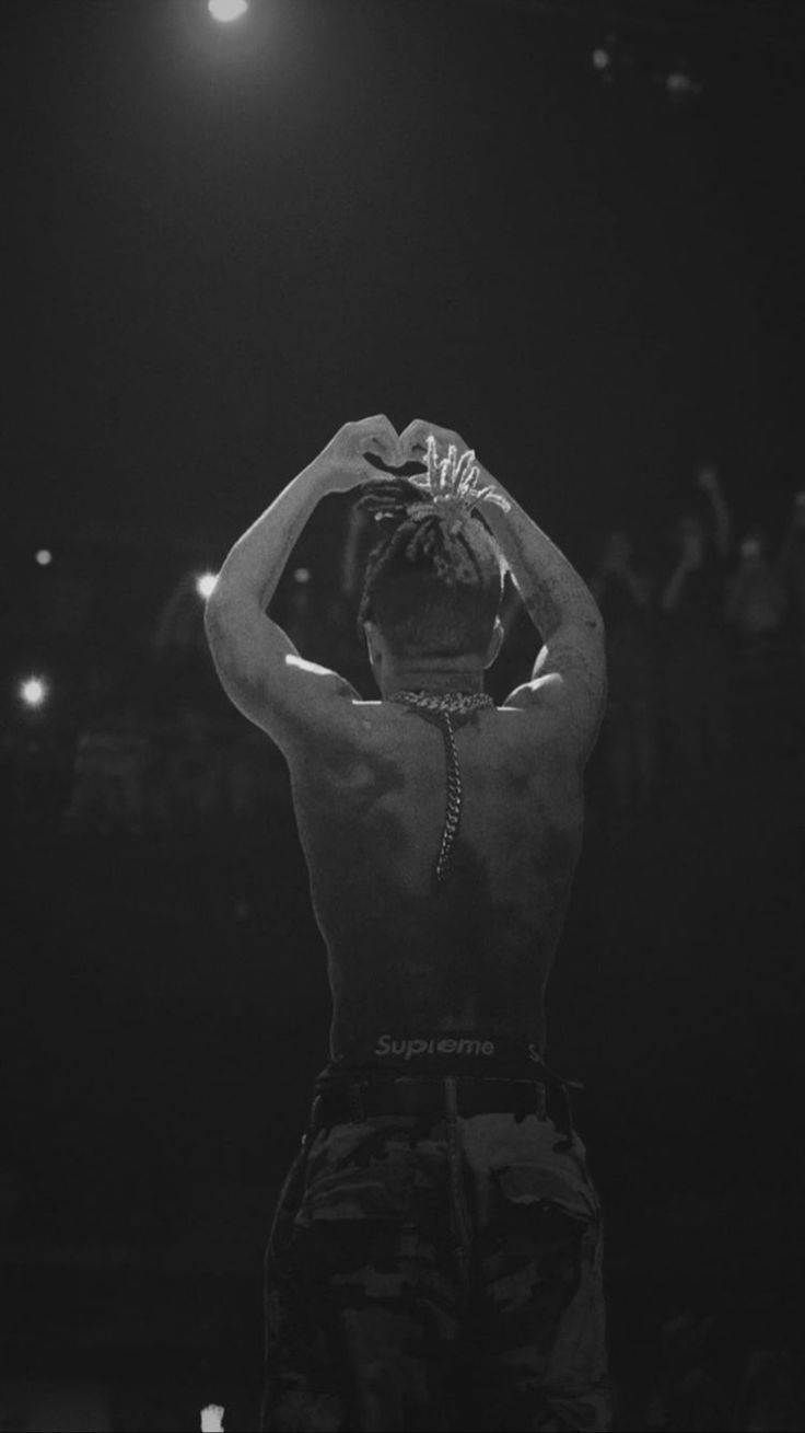 a man standing in front of a crowd holding his hands up to his head with one hand