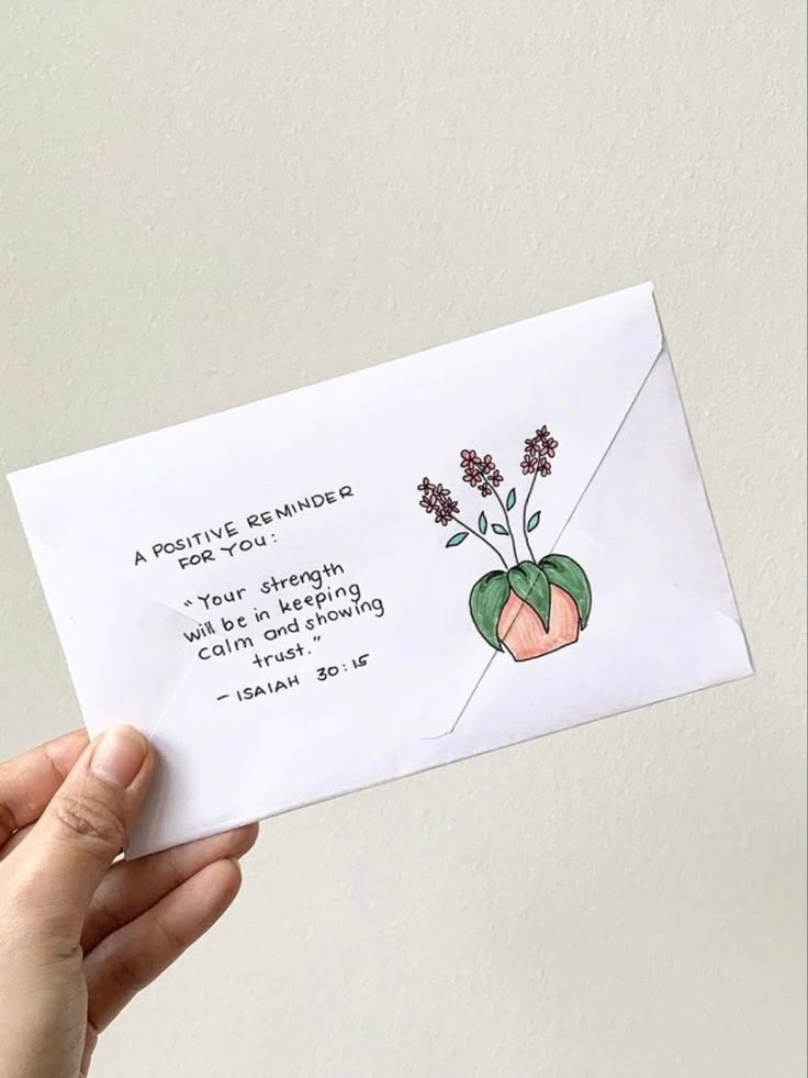 a hand holding up an envelope with flowers on it