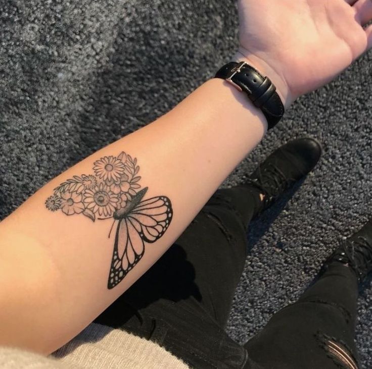 a woman's arm with a butterfly and flowers tattoo on the left side of her arm