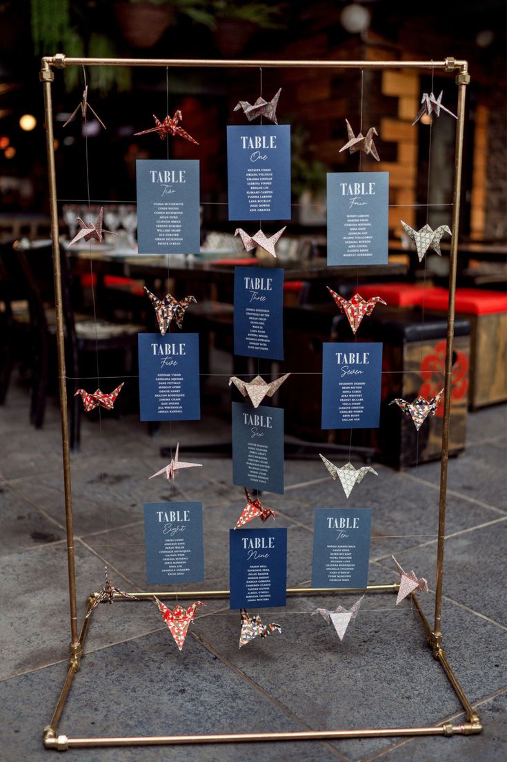 a display case filled with folded paper cranes on top of a floor next to tables