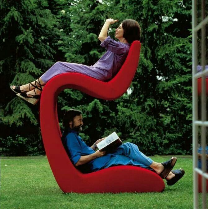 two people sitting on top of a sculpture in the shape of a heart and book