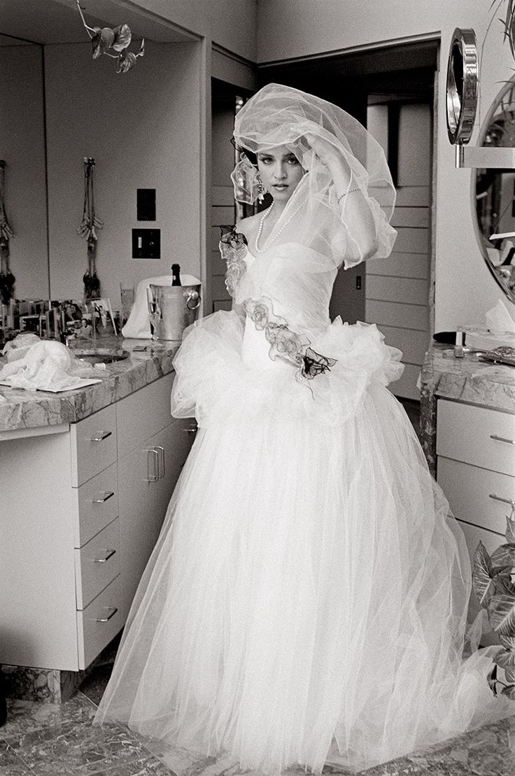 a woman in a wedding dress standing in a bathroom