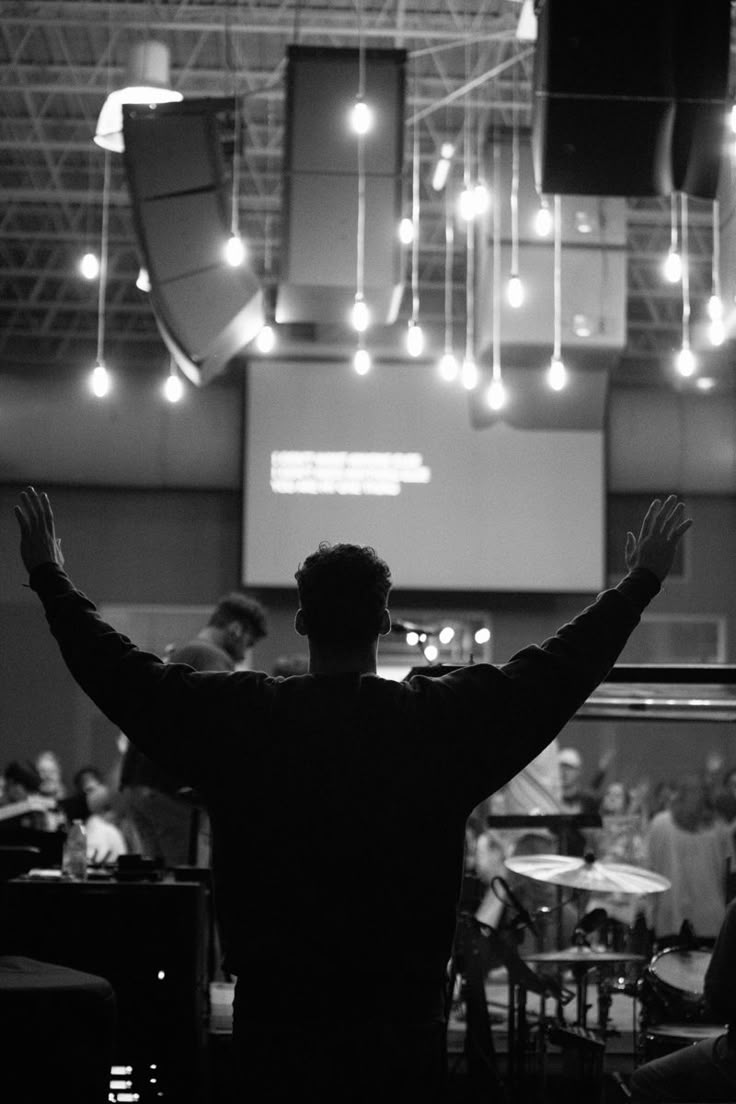 a man standing in front of a stage with his arms up and hands raised to the side