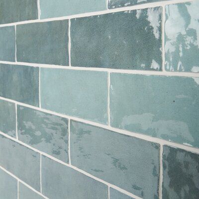 a blue brick wall that has been painted in shades of gray and green with white trim