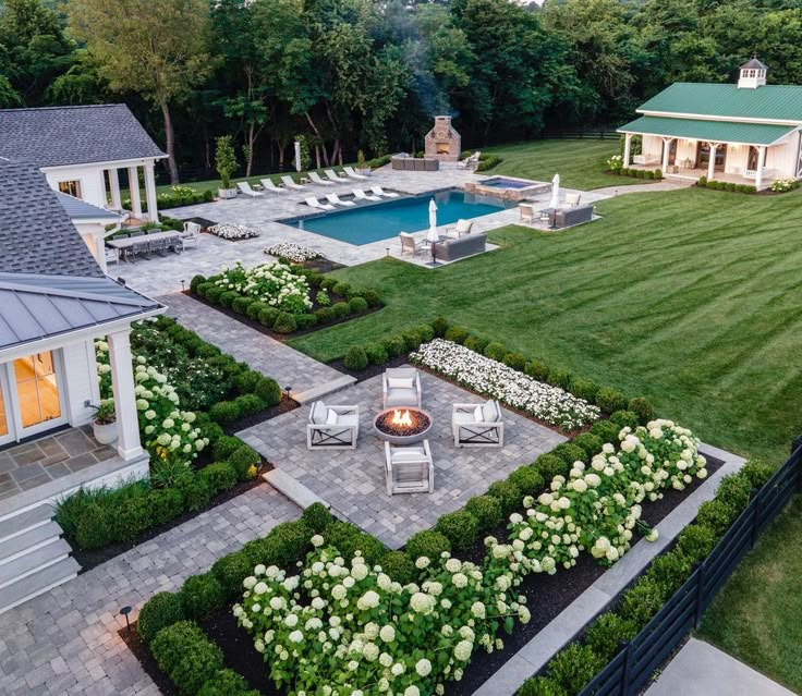 an aerial view of a house with a pool and landscaping in the foreground, surrounded by lush green grass