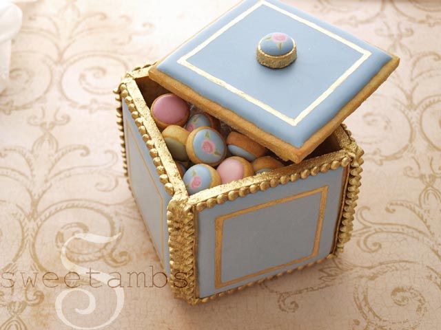 a blue and gold box filled with cookies on top of a table next to a white plate