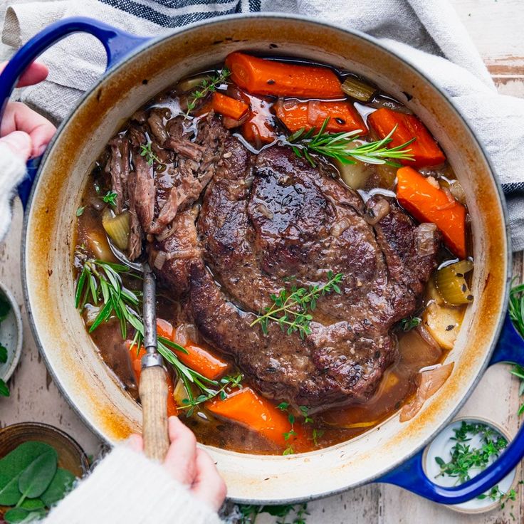 a pot filled with beef and carrots on top of a table