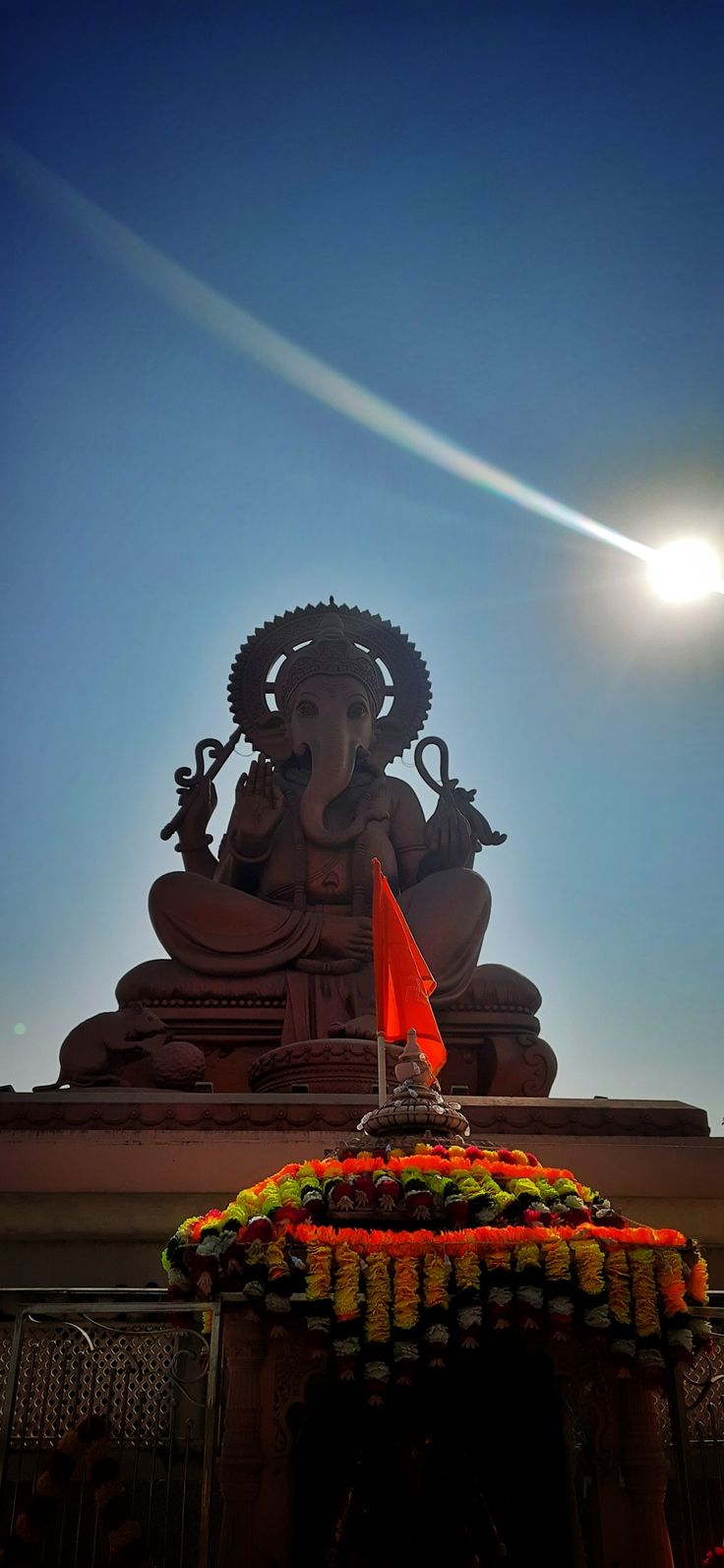 the sun shines brightly over a statue with an orange flag