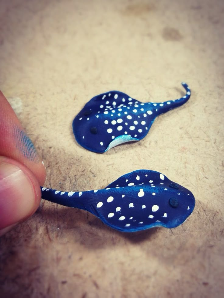 two small blue and white stingfishs being held by a finger