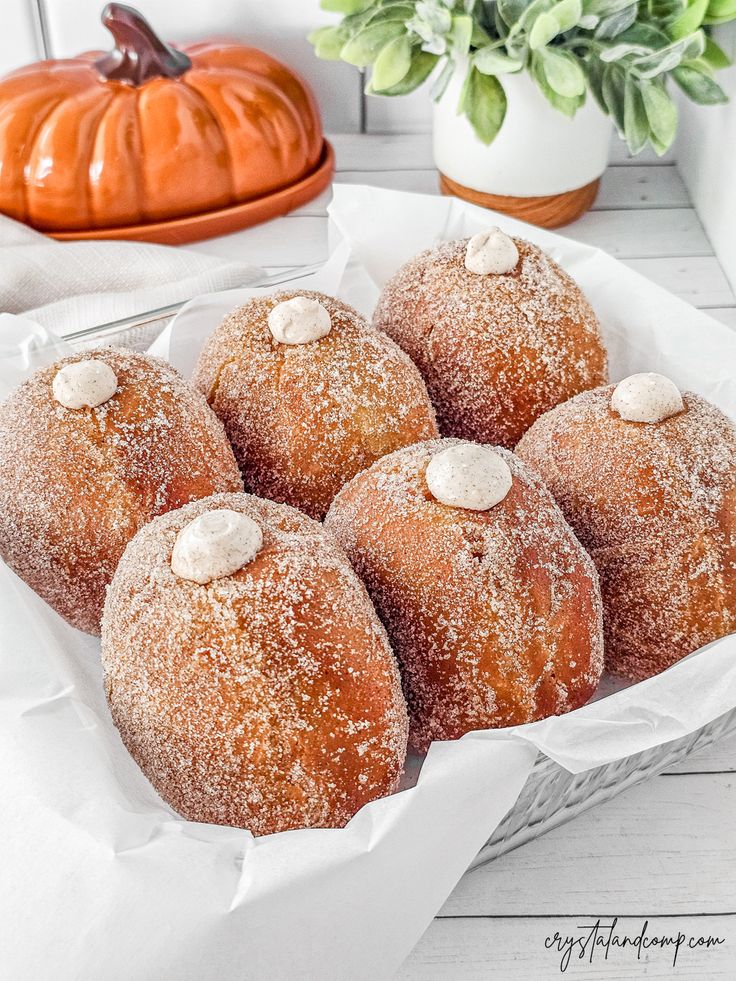 some sugar covered donuts are in a basket on a table next to a potted plant