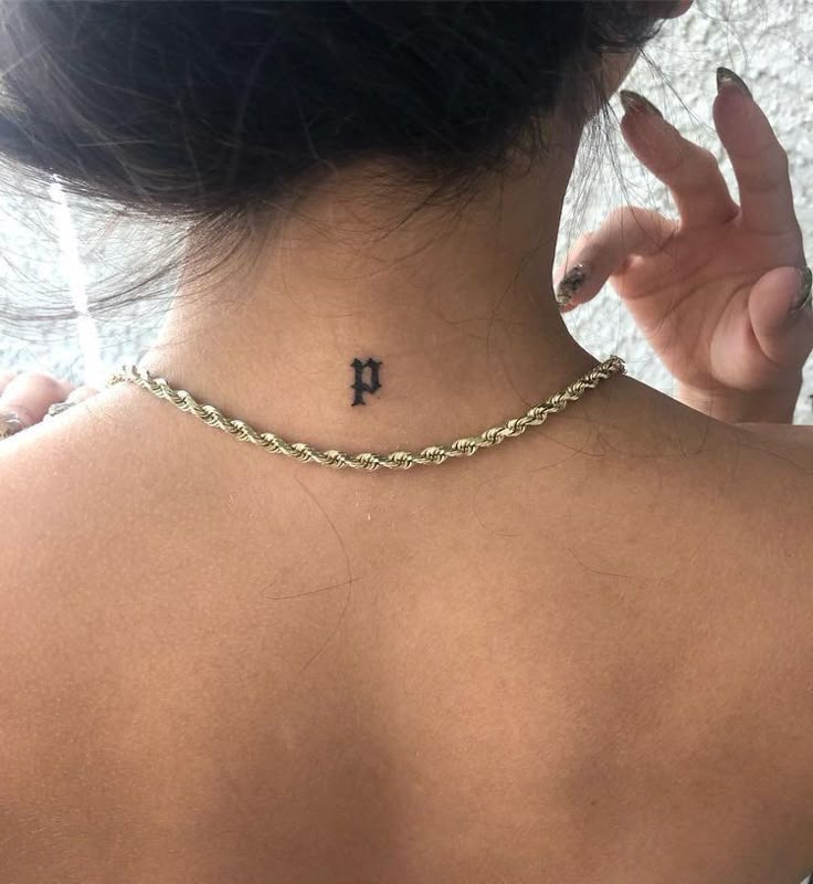 the back of a woman's neck with a cross tattoo on her left side