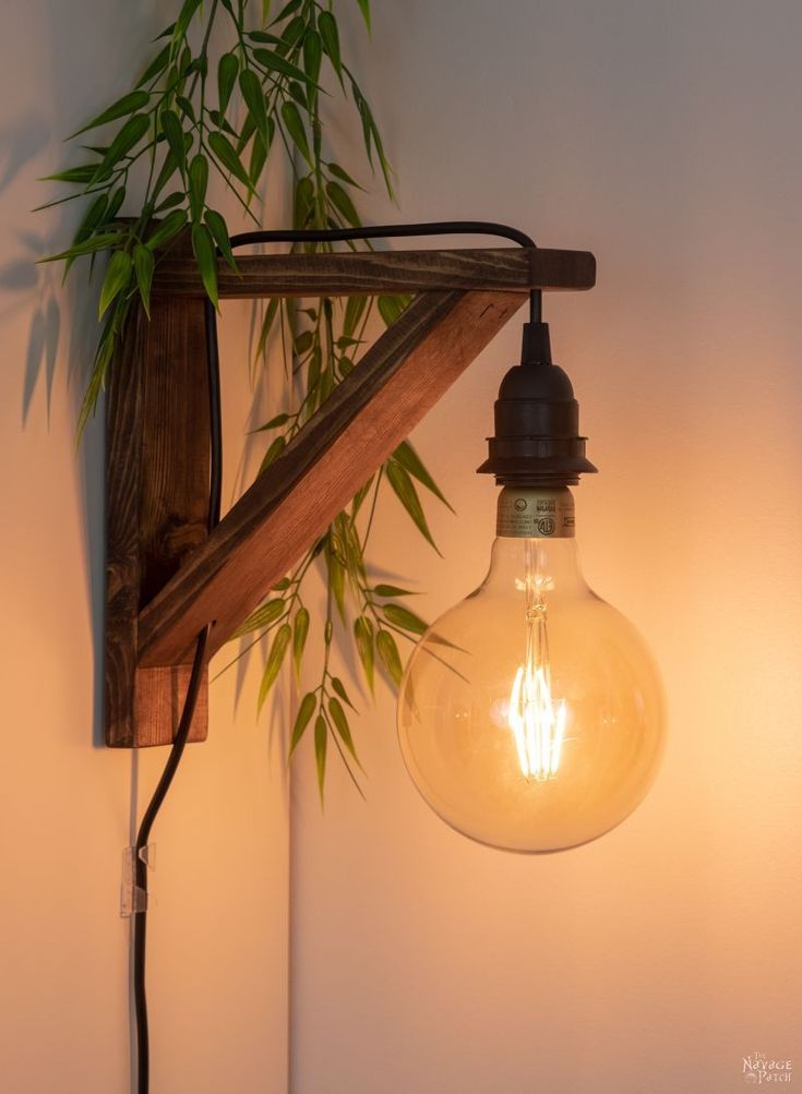 an old fashioned light bulb hanging from a wooden beam on a wall next to a potted plant