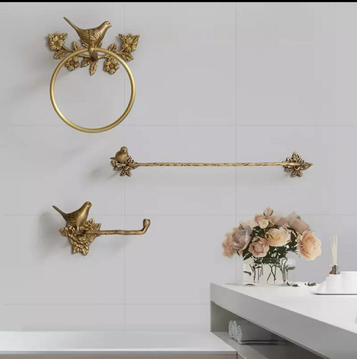 a white bathroom with gold fixtures and flowers on the counter top, next to a sink