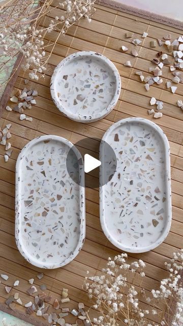 three white dishes sitting on top of a wooden table next to dried grass and flowers