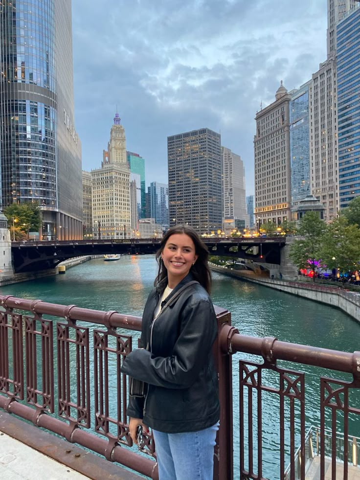 a woman is standing on a bridge overlooking the river and skyscrapers in chicago, illinois