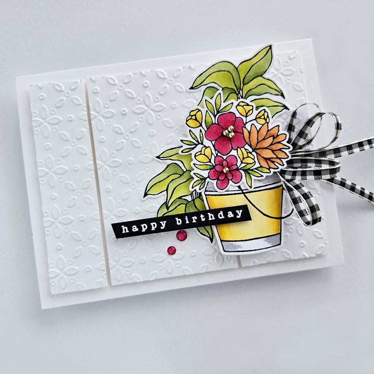 a happy birthday card with flowers in a pot on the front and black and white checkered ribbon