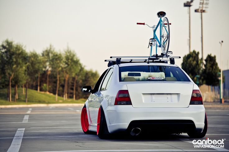 a white car with a bike on top of it's roof rack in a parking lot