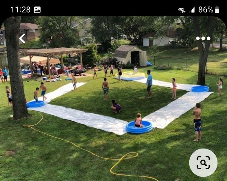 a group of people playing in a yard with an inflatable pool on the grass