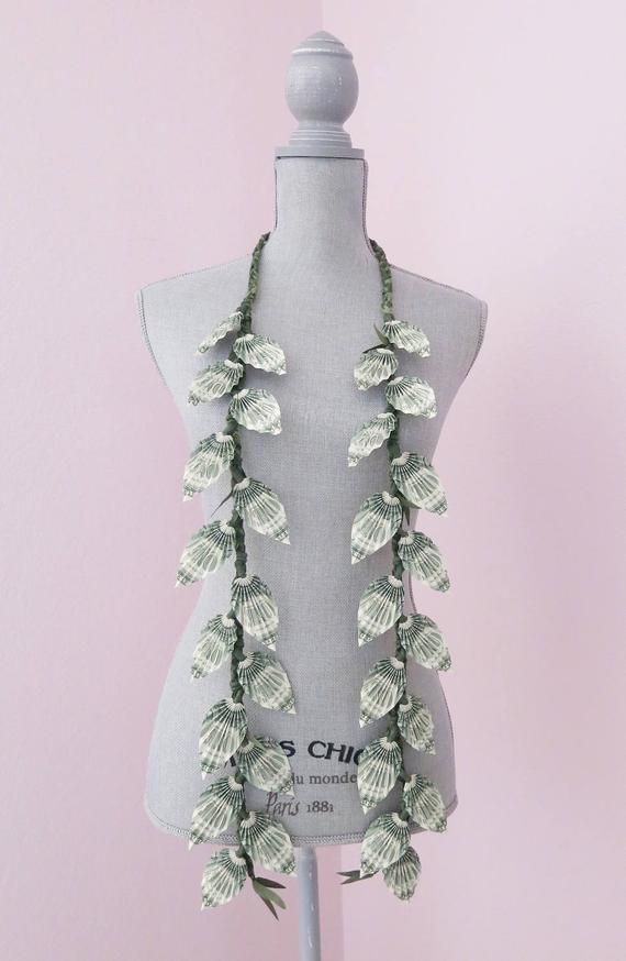 a white mannequin with green leaves on it's neck and two necklaces