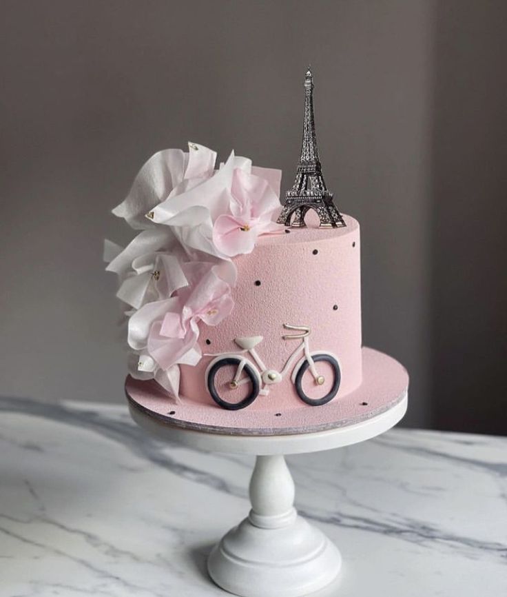 a pink cake decorated with flowers and a bicycle