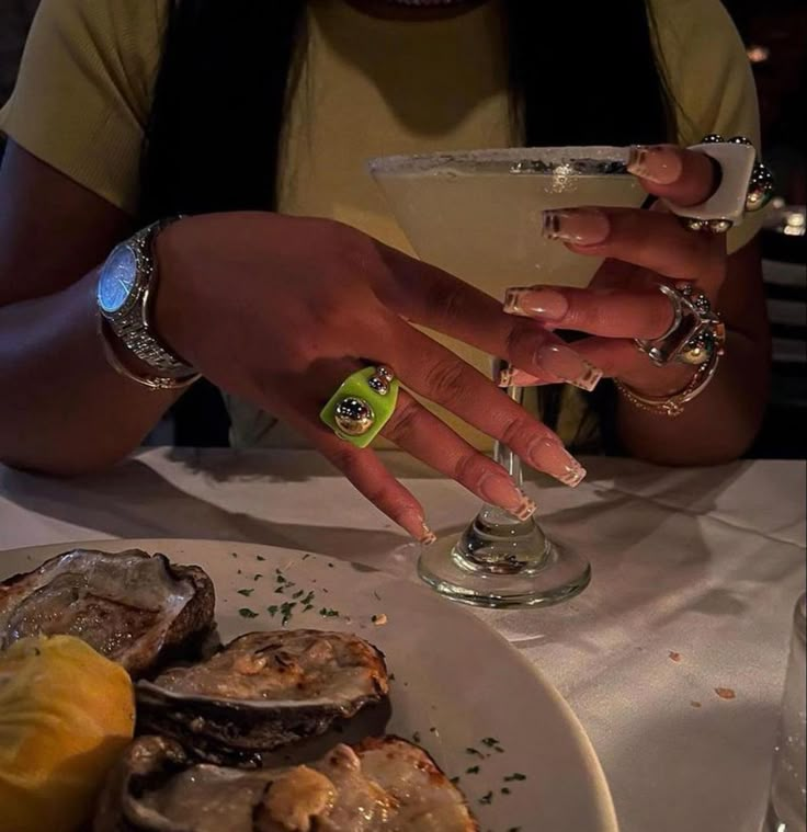 a woman sitting at a table with oysters in front of her and a drink