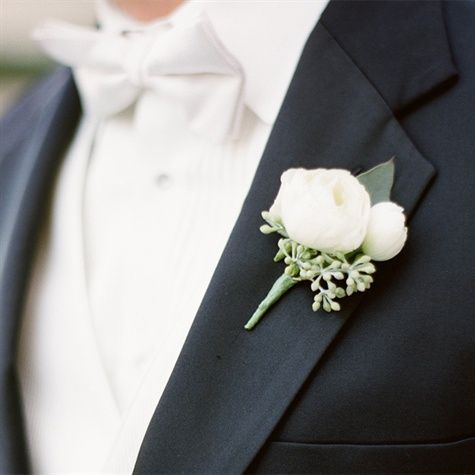 a man in a tuxedo wearing a boutonniere with white flowers