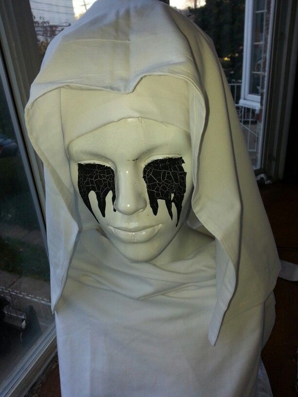 a white mannequin with black wings on it's head wearing a hood