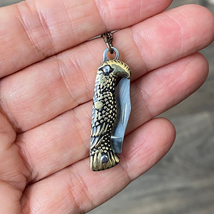 An antique-gold bird knife with a sharp blade on an brass chain. Metal: Stainless steel blade, aged brass chain Size: 1.25" L knife Lobster Clasp Available in 16", 18", and 20" chain (18" Fits Most) Chain is made in the USA, Knife is made in China Bird knife is also available on a long y-drop chain. Word to the wise: This is a real knife and the blade is sharp. Don't wear it with the knife open. Keep it out of reach of children. Use caution when opening and closing it (if you've never opened a pocket knife, please take a minute to find a YouTube video to learn). Pocket Knife Necklace, Knife Necklace, State Necklace, Figaro Chain, Figaro Chains, Brass Necklace, Aged Brass, Gold Chain Necklace, Brass Chain