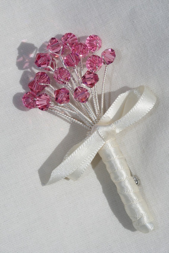 a pink flower brooch sitting on top of a white cloth