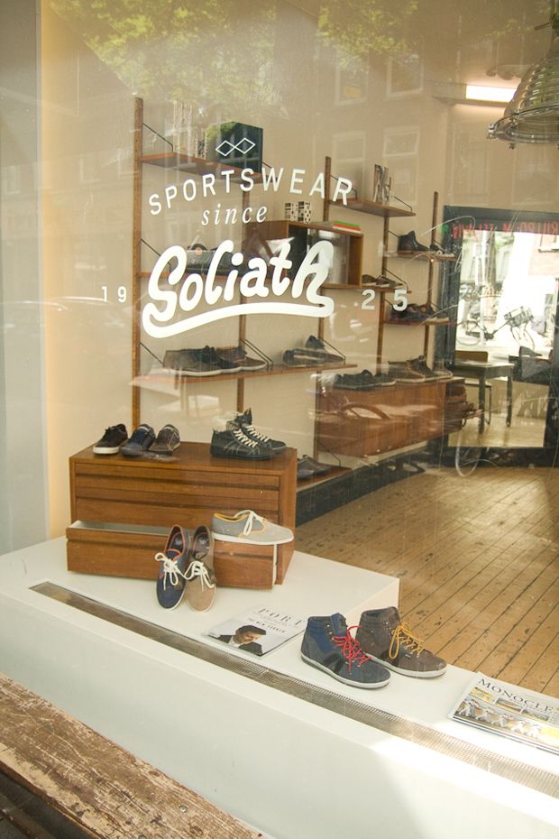 shoes are displayed in the window of a sportswear store, with an advertisement on it