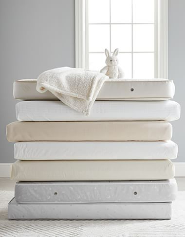 a stack of mattresses and blankets in front of a window with a stuffed animal on top